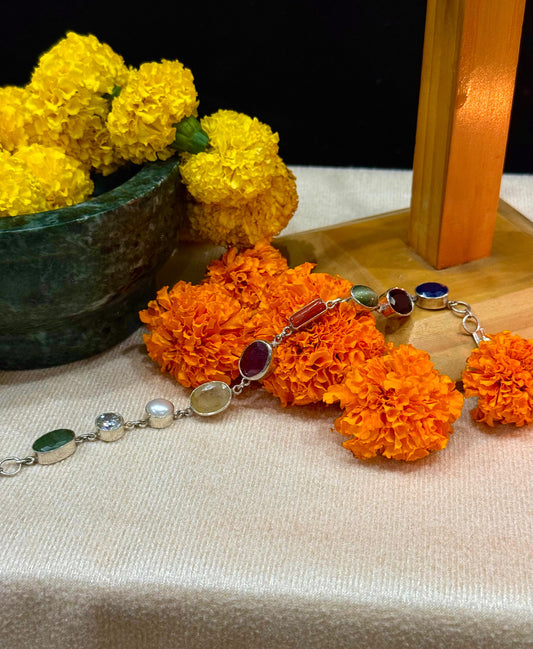 Bracelet with orange floral poms and silver beads on a textured surface with yellow flowers.