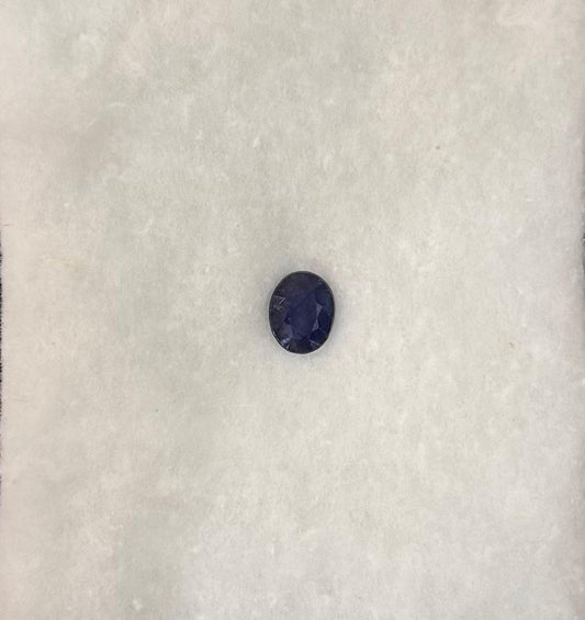 Single dark blue gemstone on a textured white background