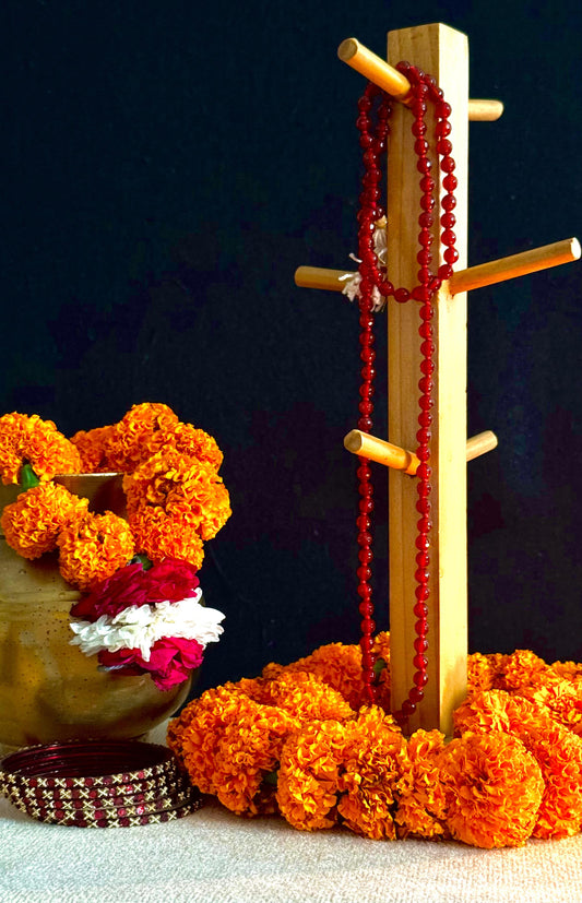 Wooden stand with red beads, marigold flowers, and a decorative item on a dark background
