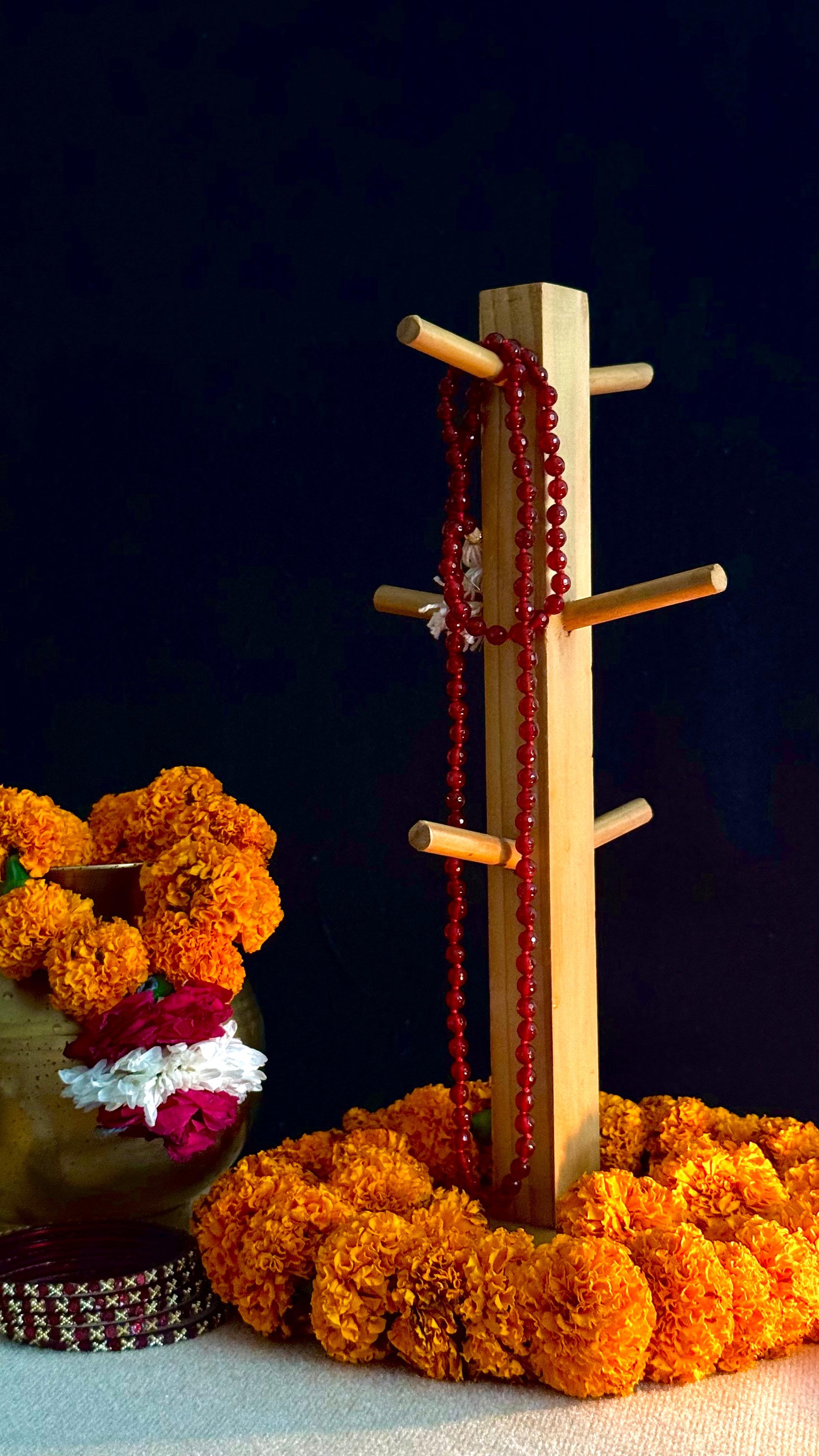 Wooden jewelry stand with red beads on a dark background