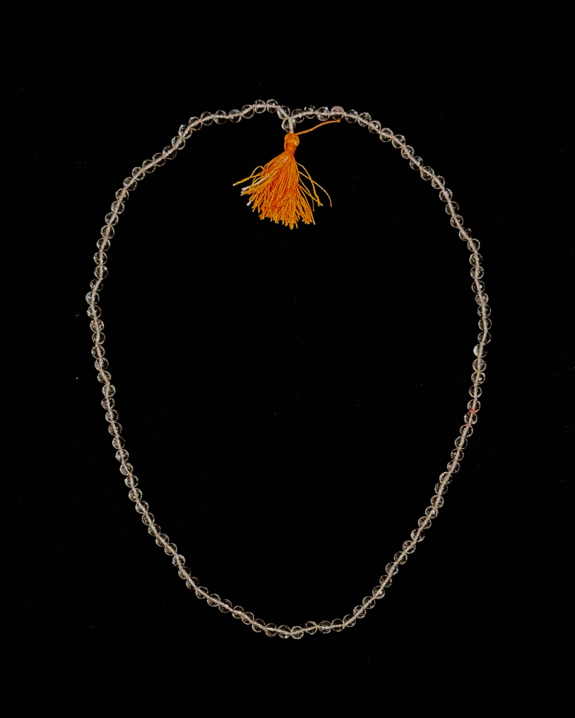 Necklace with an orange tassel on a black background