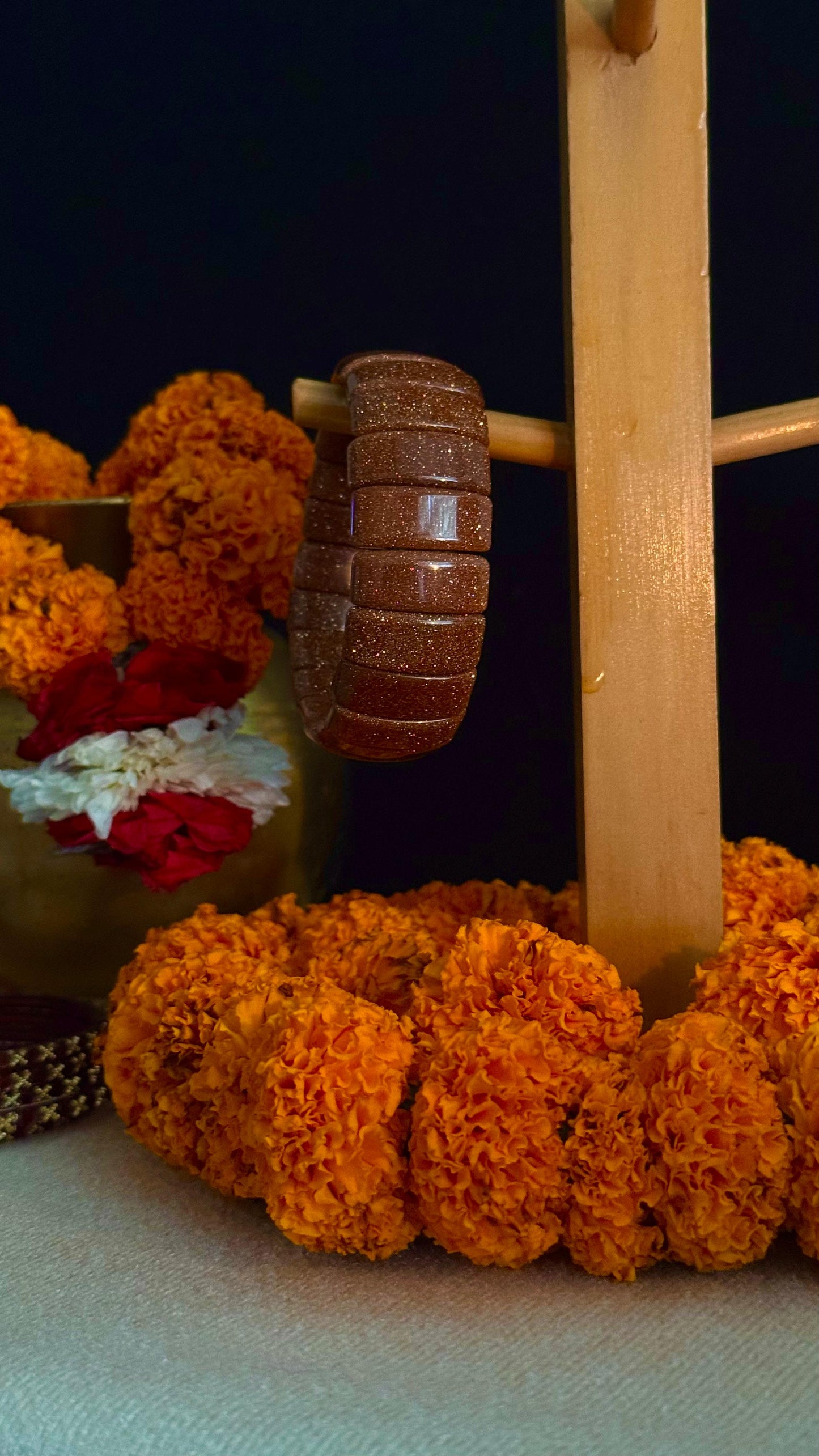Wooden mace with marigold flowers on a dark background